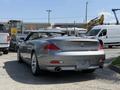 A silver 2004 BMW 6-Series convertible parked with its top down showcasing a sleek design and dual exhaust pipes