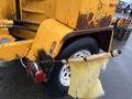 A rusty yellow Bandit 200 wood chipper with a worn tire and a frayed tarp attached to the side