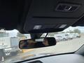 A 2021 Ford Explorer with a view of the rearview mirror showing a driver's hand holding a phone and overhead controls