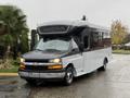 A 2019 Chevrolet Express shuttle bus with a black and white exterior features large side windows and an elevated front section for driver visibility