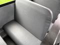 A single gray bus seat with a textured surface and a clean design positioned beside a window in a bus interior