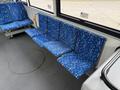 Four blue patterned seats designed for public transport in a bus interior with a grey floor