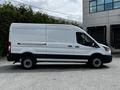 A white 2022 Ford Transit van is parked, showing its side profile with a black stripe along the bottom and black wheels