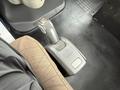 The gear shift lever of a 2012 Volvo VNL positioned beside a brown seat on a black floor mat