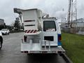 A 2009 Ford Econoline van with a white body and a raised bucket lift attached at the rear, featuring safety markings and a ladder rack on the back