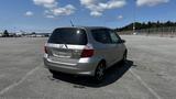 A 2006 Honda Fit parked on a pavement with a gray exterior and a visible hatchback design