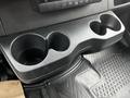A black plastic cup holder with two compartments designed for holding cups or bottles inside a 2021 Mercedes-Benz Sprinter