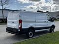 A 2018 Ford Transit van in white with black accents parked with its rear facing the viewer