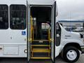 A 2016 Ford Econoline bus with an open door displaying steps and a wheelchair accessibility feature leading into the driver's area