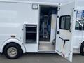 A white 2014 Chevrolet Express with an open side door revealing an interior space with blue seats and storage compartments