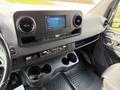 Interior view of a 2019 Mercedes-Benz Sprinter with a dashboard featuring a touchscreen display and climate control knobs along with dual cup holders