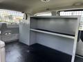 A 2011 Dodge Grand Caravan featuring a gray interior with a spacious cargo area and a metal storage unit on the left side with hooks and a flat shelf for organization