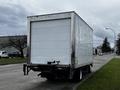 A 2018 Isuzu NRR box truck parked with a blank rear panel and a white exterior featuring standard tail lights and an attached hitch
