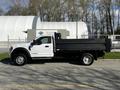 A white 2018 Ford F-550 flatbed truck parked on the street with a black flatbed and a single cab design