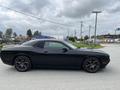 A black 2017 Dodge Challenger parked on a road showing a sleek profile and sporty design with black alloy wheels.