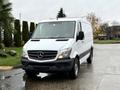 A white 2017 Mercedes-Benz Sprinter van with a black grille and side windows parked on a wet surface facing forward