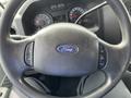 A close-up of the steering wheel of a 2009 Ford Econoline featuring the Ford logo and buttons for controlling various functions