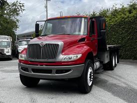 A red 2011 International 4400 truck with a silver grille and flatbed design positioned at the forefront