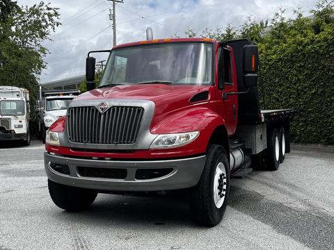 A red 2011 International 4400 truck with a silver grille and flatbed design positioned at the forefront