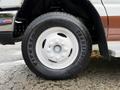 Close-up of the white wheel and tire of a 2014 Ford Econoline van showing the Firestone Transforce HT tire tread and the hubcap design