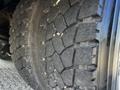 Close-up of a tire from a 2004 Freightliner M2 showing deep treads with some wear and dirt visible on the surface
