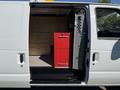 A white 2011 Ford Econoline van with the side door open revealing a red cabinet inside along with drawers and a detailed interior storage space