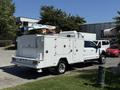 A white 2024 Ford F-550 Super Duty truck equipped with a rear-mounted utility body and a lifting boom on top