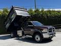 A brown 2015 RAM 5500 dump truck with a tilted dump bed showcasing its cargo capacity