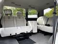 Interior of a 2003 Mitsubishi 7 Passenger Van featuring two front seats and three rear seats with grey upholstery and a central armrest