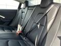 Interior of a 2019 Tesla Model 3 showing the rear seats with black leather upholstery and seat belts fitted
