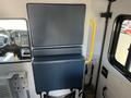 A blue padded seatback mounted on the wall of a vehicle with a yellow grab handle beside it