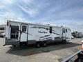 A 2013 Outdoor Wind River RV parked with five wheels and a slide-out section on the side