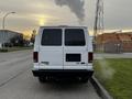 A white 2011 Ford Econoline van parked on a road with no visible license plate at the back