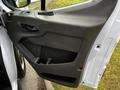 A 2020 Ford Transit van door is open displaying the interior handle and storage compartments