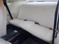 A 1974 Dodge Challenger featuring a cream-colored upholstered rear seat with vertical stitching and black floor mats