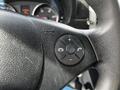 Close-up of a steering wheel control panel featuring buttons for volume adjustment, phone functions, and a central control knob