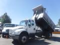 A 2005 Freightliner M2 106 Medium Duty truck with a raised dump bed is parked in a lot