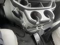 Interior view of a 2009 Ford Econoline showing a center console with two cup holders and a mounted communication device