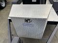 A silver diamond-plate storage box with a lock on top mounted on a trailer or vehicle