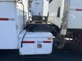 A white storage compartment attached to a 2007 International 7300 truck with a latch and red stripes on the side