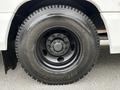 Close-up of a black tire mounted on a white bus with prominent tread and a five-bolt rim featuring a central hub and branding on the sidewall