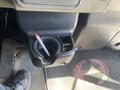 A black cup holder with a pen inside and a textured floor mat featuring a red logo