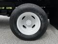 Close-up of a white tire mounted on a wheel of a 2021 Ford E-450 showing the Firestone logo and tread design