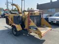 A 2010 Vermeer Corporation BC1200XL wood chipper featuring a large chute, a hopper in the front, and a towing hitch with visible wear and tear on the exterior