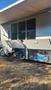 A 2007 Winnebago Adventure with open storage compartments revealing various items inside, including a blue container and tools
