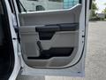 A white 2017 Ford F-250 SD truck door with a gray interior panel featuring a door handle a window crank and storage compartment