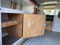 Interior view of a 2012 GMC Savana showing wooden shelves and cabinets with a partially open wooden door
