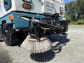 A 2001 Tennant 830-II street sweeper with a round rotating broom attachment in the foreground