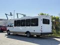 A white 2017 Chevrolet Express van with large windows and a shuttle bus configuration parked at an industrial area