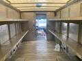 Interior of a 2012 Ford Econoline with metallic shelving on both sides and a view to the front cab area